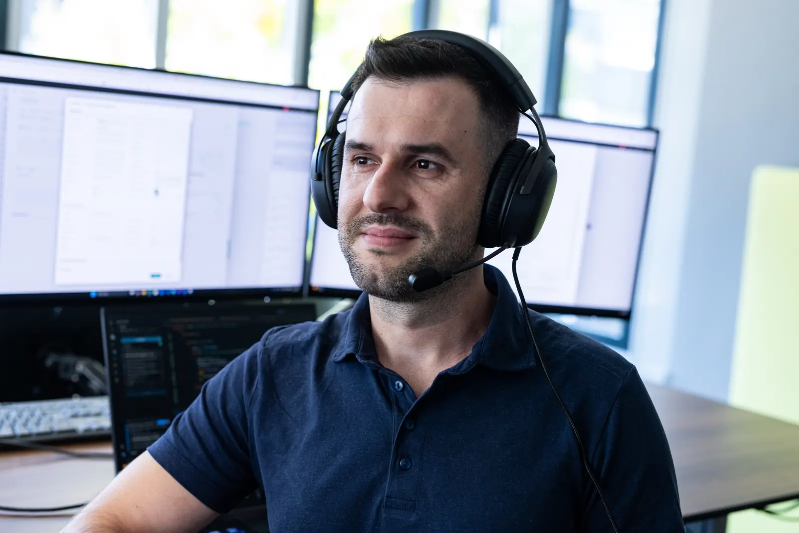 Employee with a headset in front of several screens