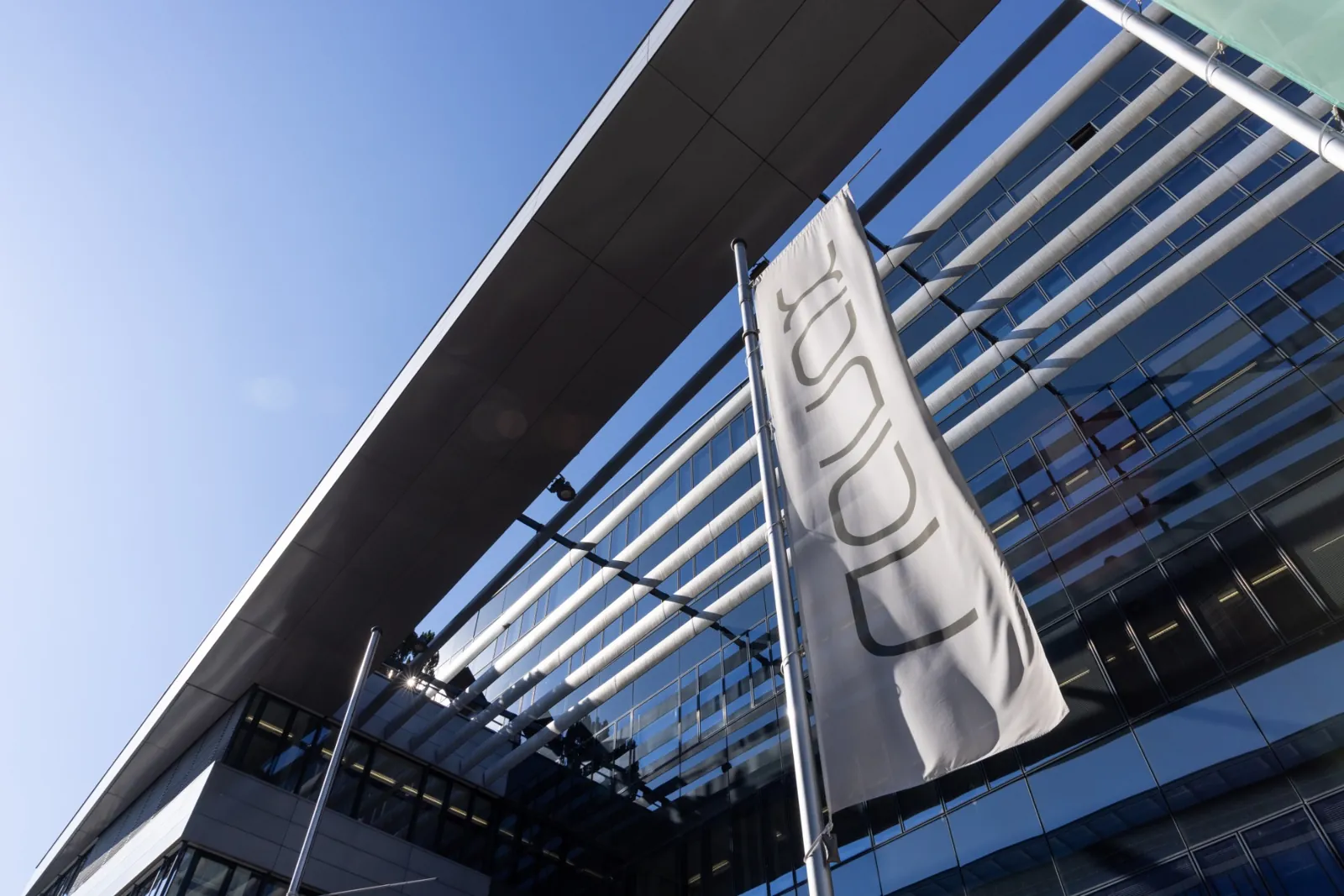 Fahne mit NAVAX-Logo vor der Glasfassade des Bürogebäudes