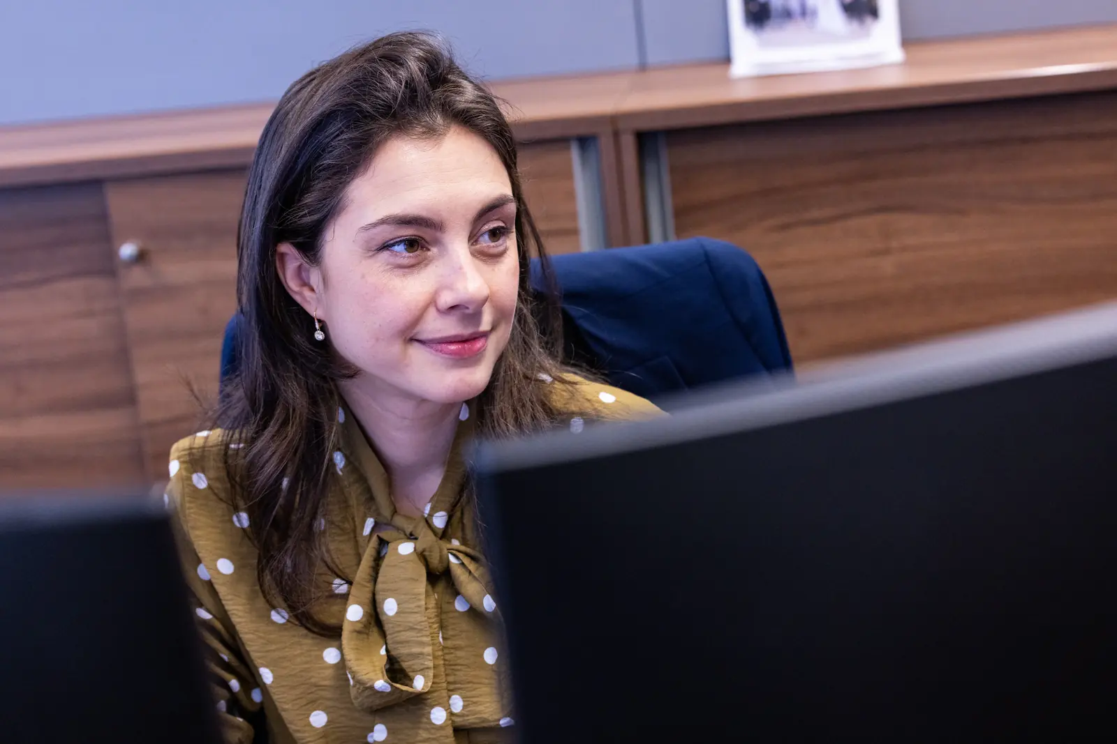 Employee at her desk behind two screens
