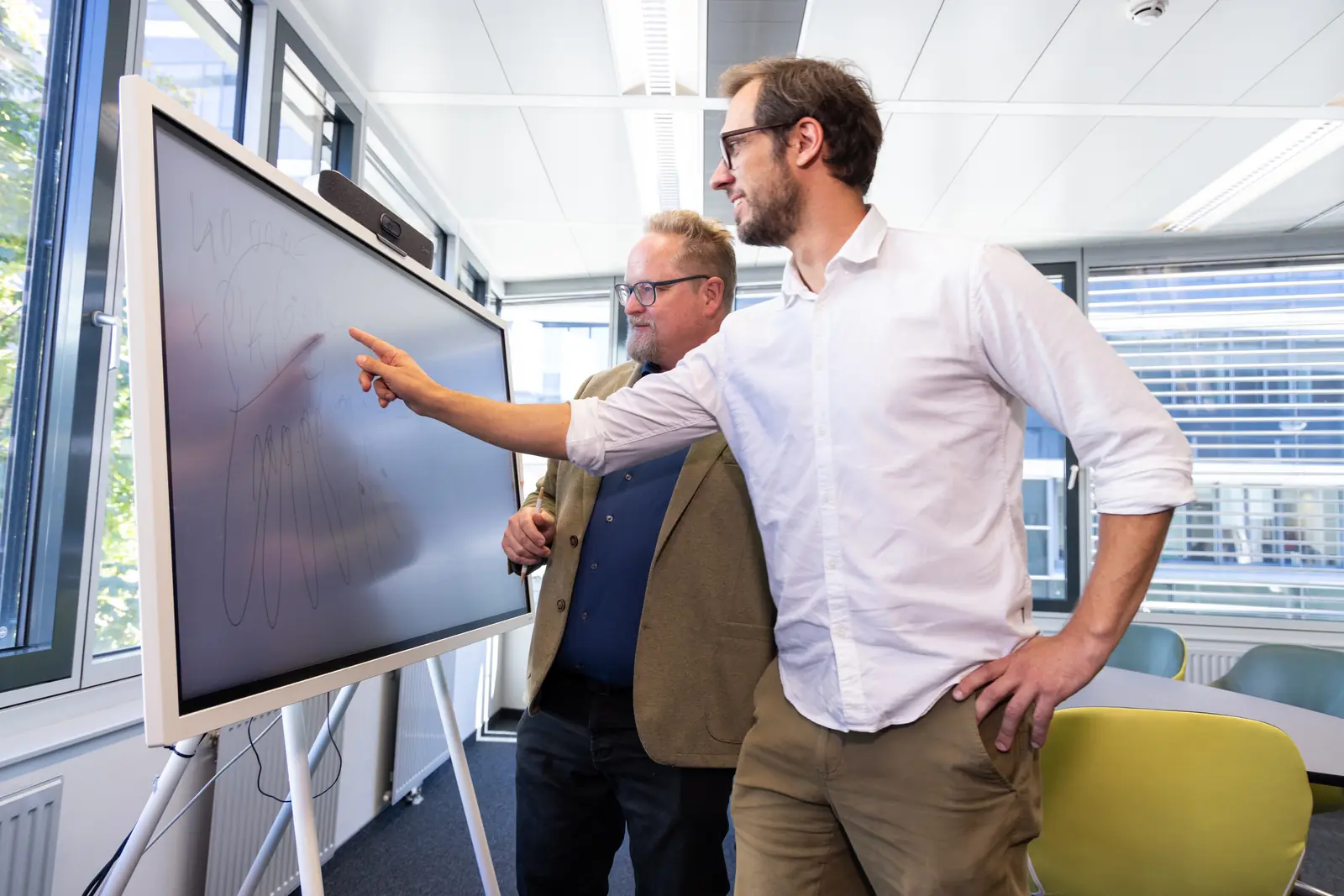 Zwei Kollegen besprechen eine Skizze an einem digitalen Whiteboard