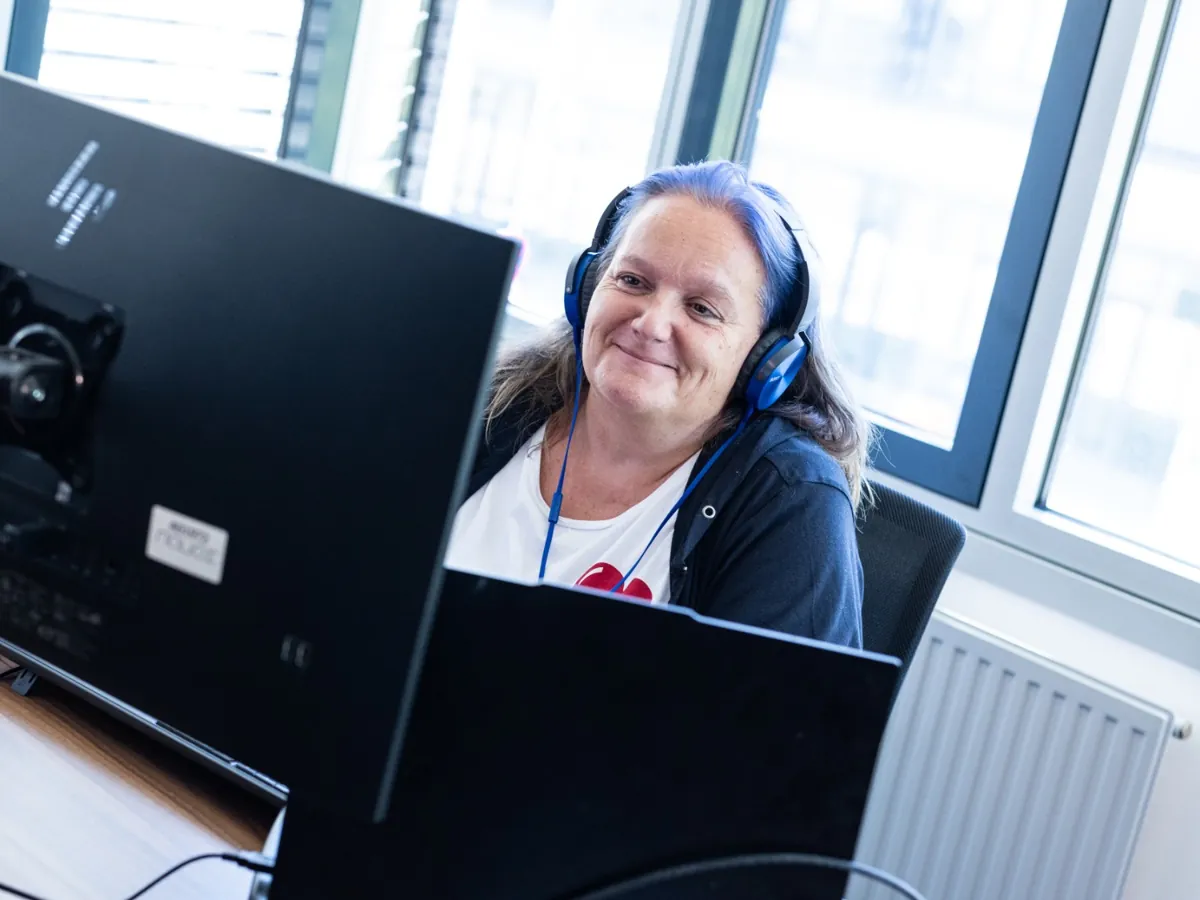 Mitarbeiterin mit Headset an zwei Bildschirmen