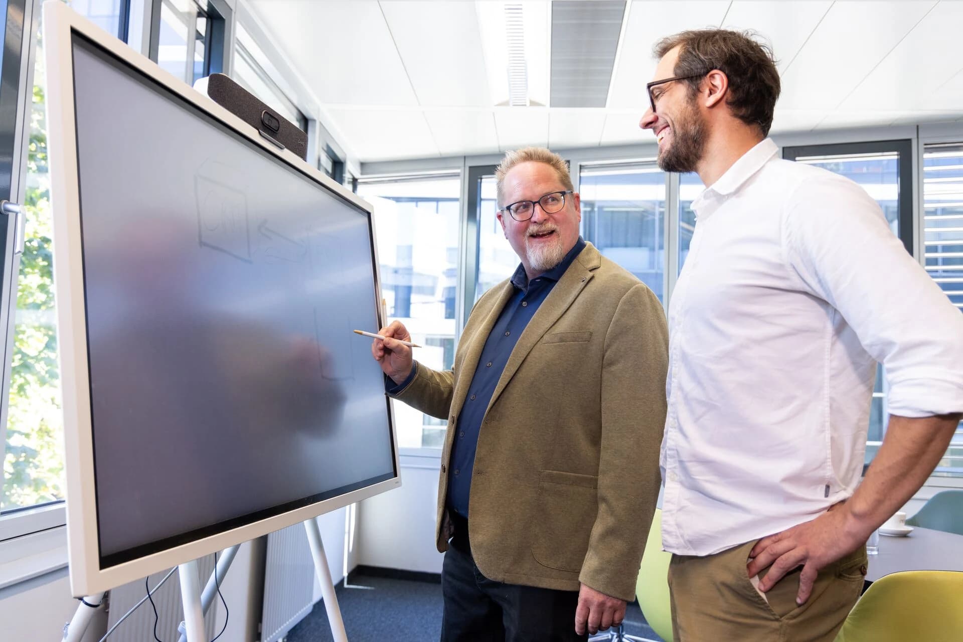 Zwei Personen skizzieren einen Ablauf am digitalen Whiteboard
