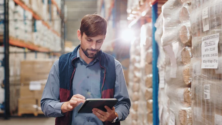 Mann geht mit ERP Software durch die Gänge im Lager eines Großhandel 