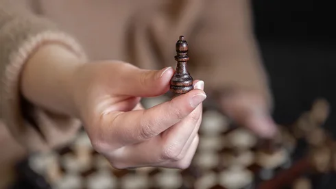 Eine Frau hält eine Schachfigur in die Kamera