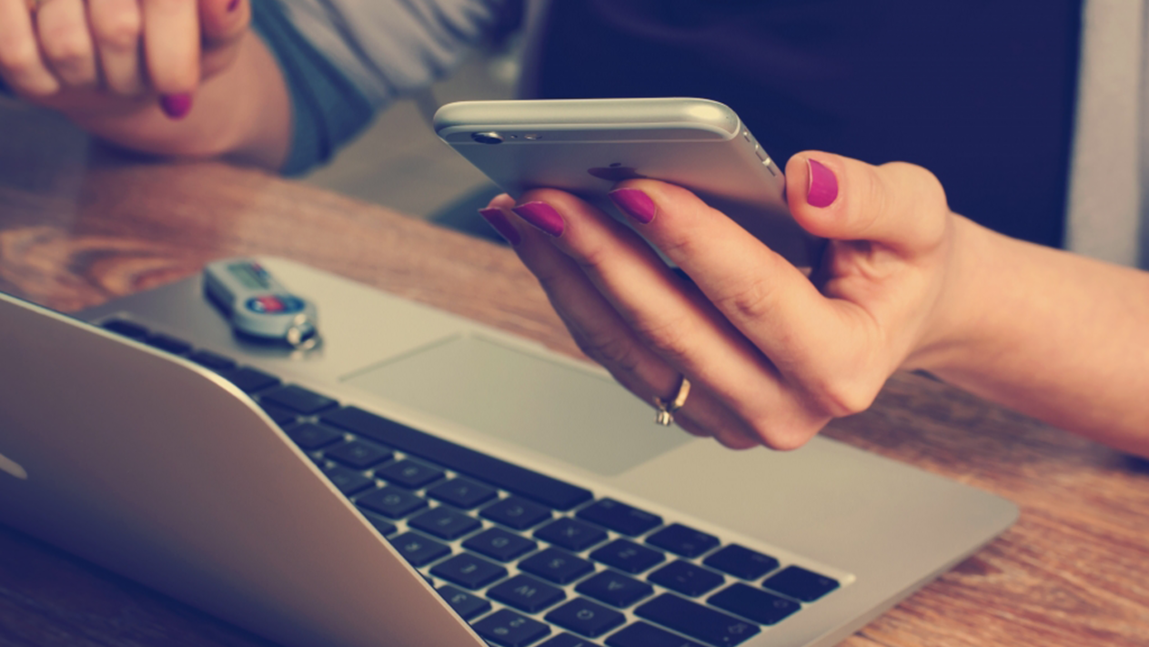 Person ist am Handy und Laptop
