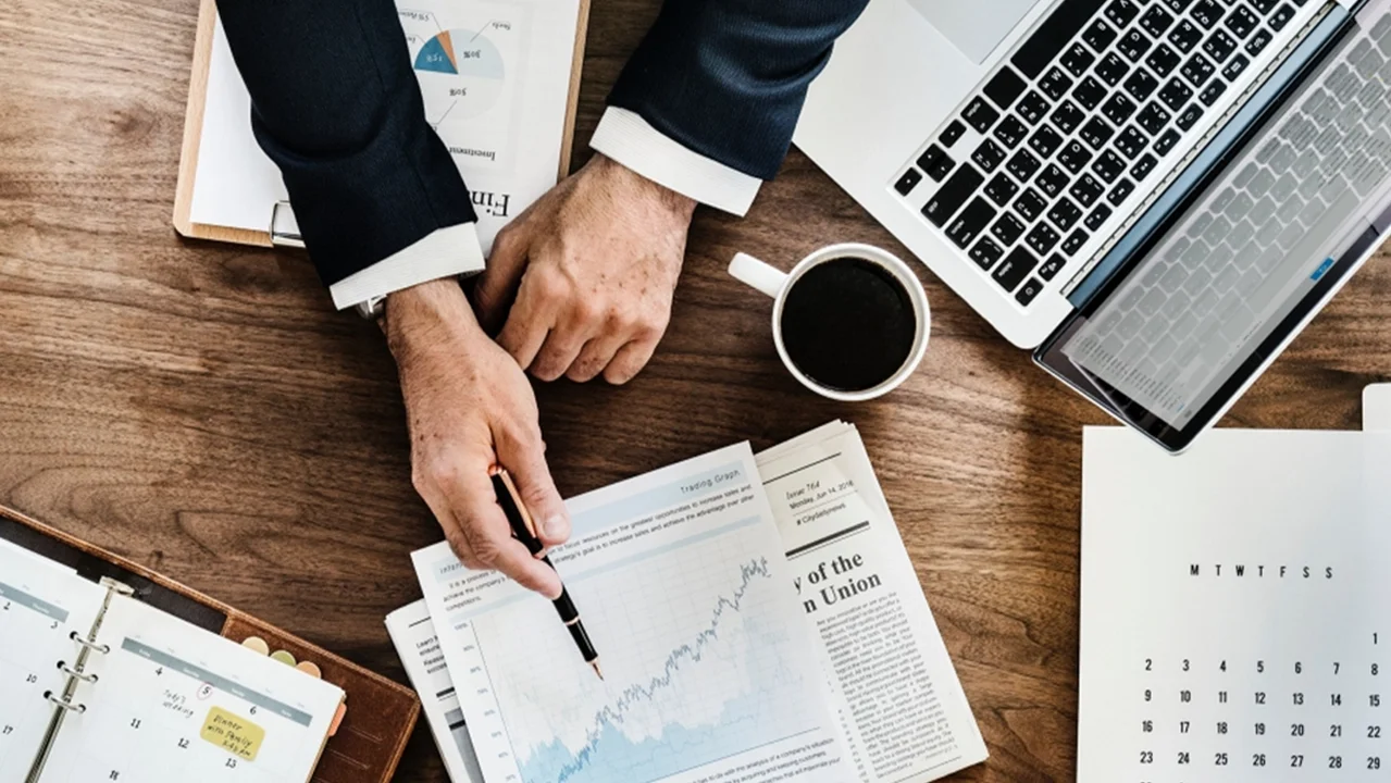 Person zeigt auf Statistiken, die auf Tisch liegen