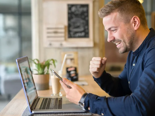 Mann freut sich vor Laptop