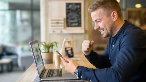 Mann freut sich vor Laptop