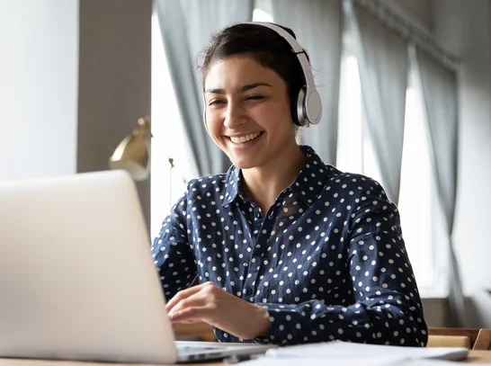 Eine Frau schaut auf Laptop und grinst