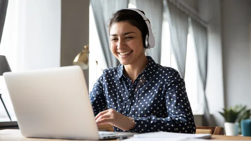 Eine Frau schaut auf Laptop und grinst