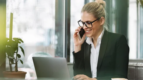 Eine Mitarbeiterin ist am Telefon vor Laptop