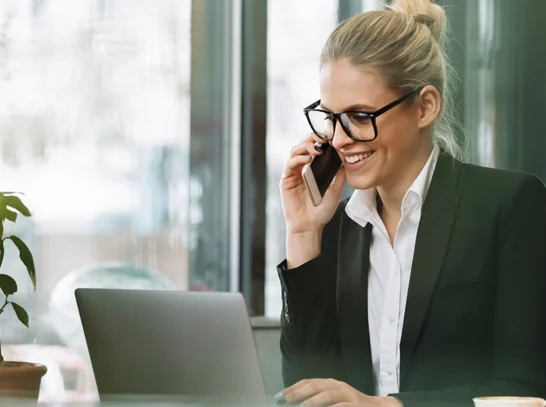 Eine Mitarbeiterin ist am Telefon vor Laptop
