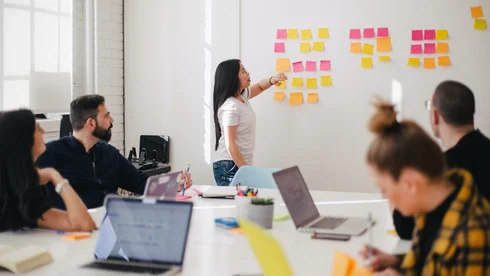 Eine Frau schreibt auf Post Its an der Wand