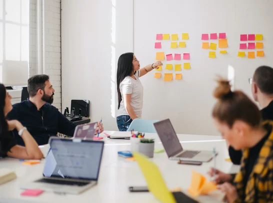 Eine Frau schreibt auf Post Its an der Wand