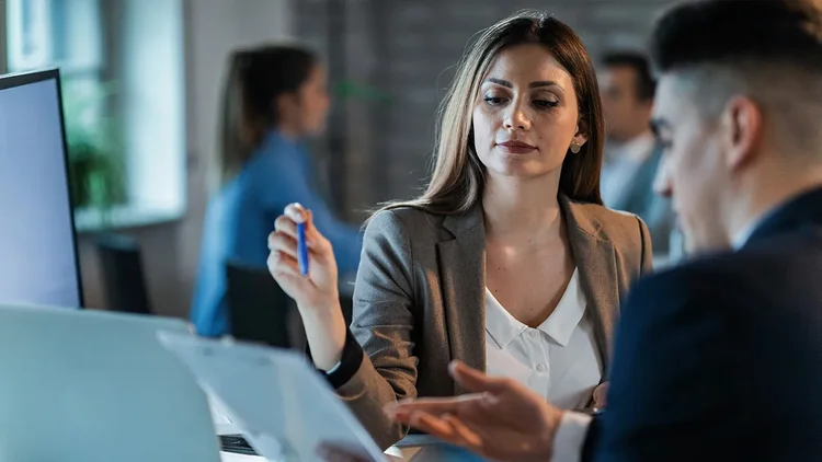 Frau erklärt Mann etwas auf einem Bildschirm und zeigt Marketing Automation