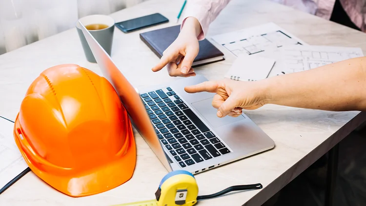 Menschen zeigen auf Laptop und besprechen Digitalisierung im Bau