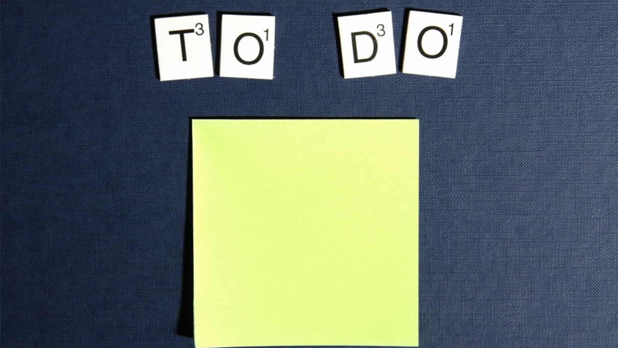 Person hat ein Post-It und eine To-Do Liste