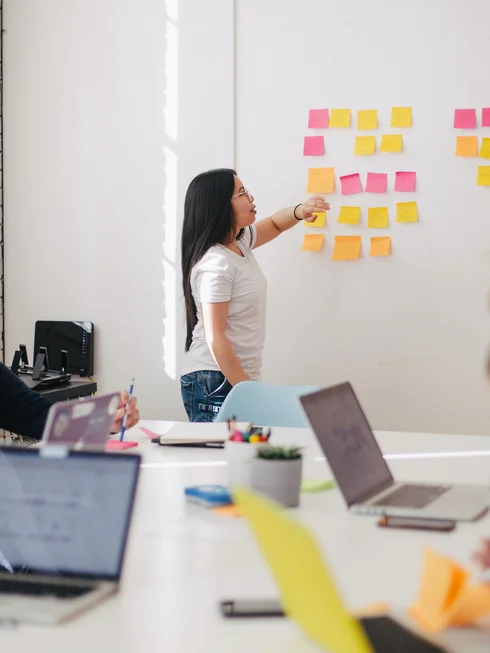 Eine Frau schreibt auf Post Its an der Wand
